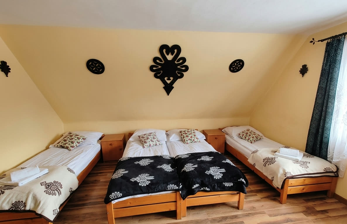 Pokój czteroosobowy nr 3 — łóżka i kuta parzenica na ścianie