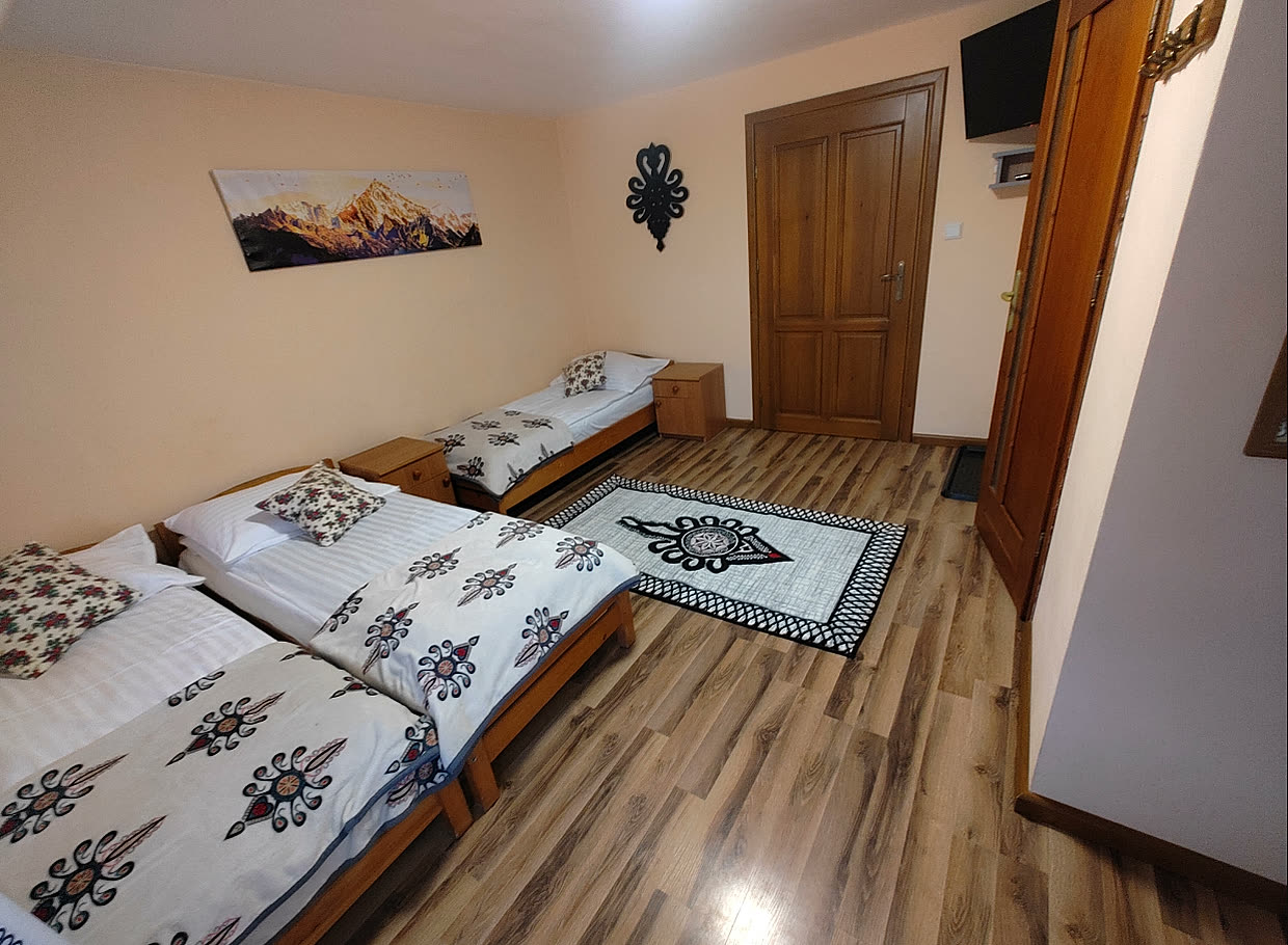 Pokój trzyosobowy nr 5 — łóżka przykryte góralską pościelą